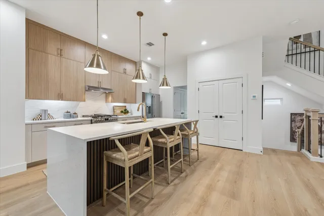 a kitchen with stainless steel appliances kitchen island granite countertop a table chairs sink and cabinets