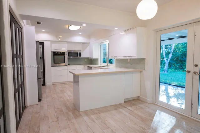 a view of a kitchen with kitchen island a sink stainless steel appliances and cabinets