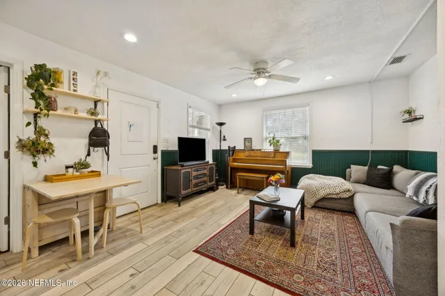 a living room with furniture and a flat screen tv with kitchen view