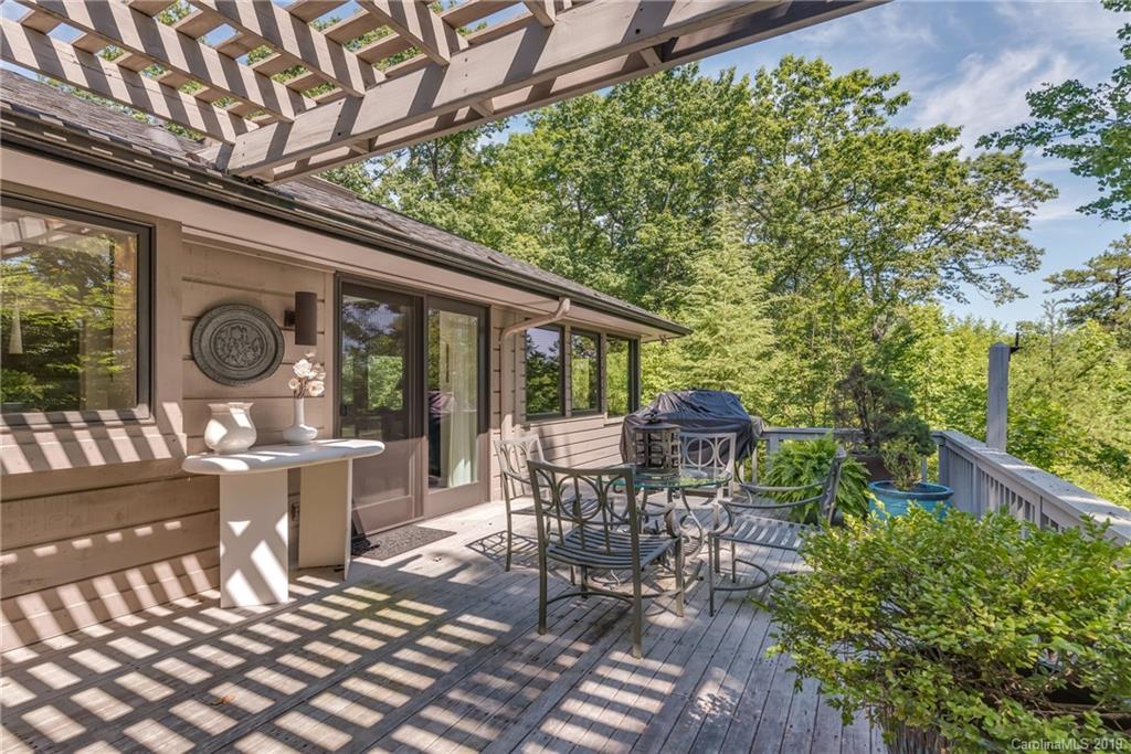 320 Ridgetop Road Tryon, NC 28782 - Photo 27 of 36 a view of a patio with table and chairs potted plants and floor to ceiling window