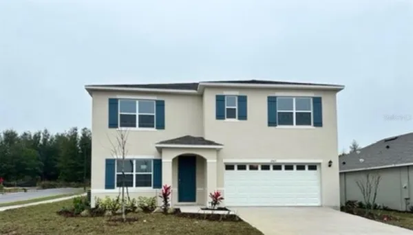 a front view of a house with plants and garage