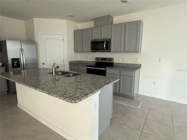a kitchen with granite countertop a sink a counter top space appliances and cabinets