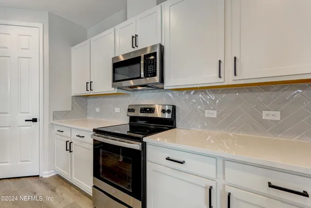 a kitchen with white cabinets and appliances