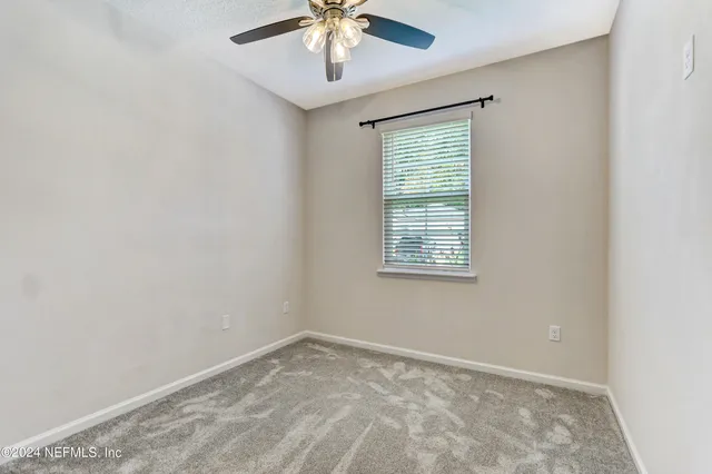 an empty room with a window and a fan