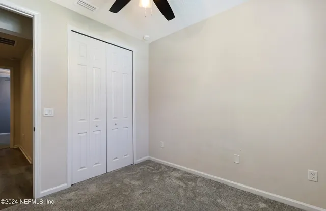 an empty room with closet and chandelier fan