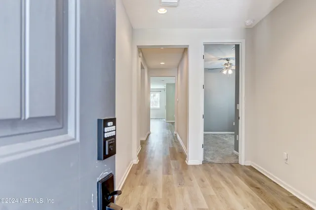 a view of a hallway with wooden floor and a bathroom