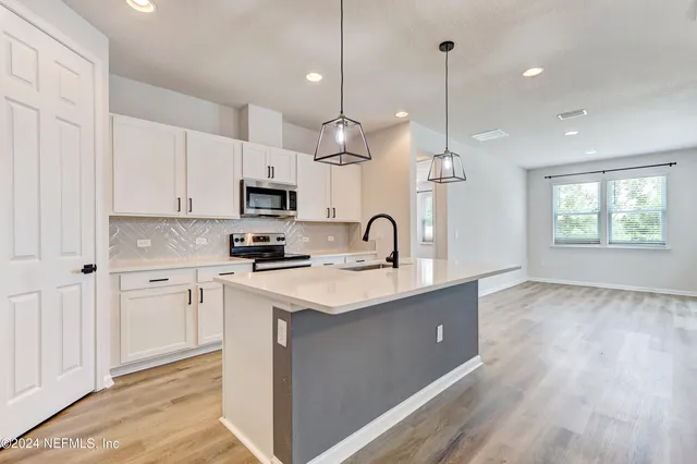 a kitchen with kitchen island white cabinets a sink a window and appliances