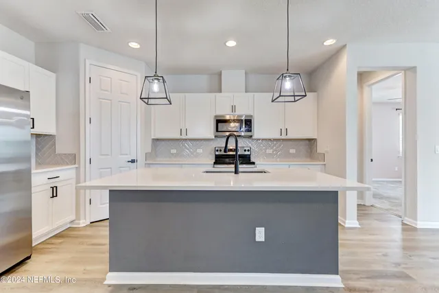 a kitchen with kitchen island a sink stainless steel appliances and cabinets