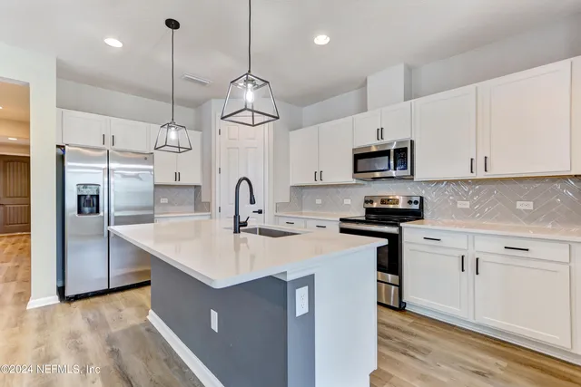 a kitchen with stainless steel appliances granite countertop a sink a stove a refrigerator and island with wooden floor