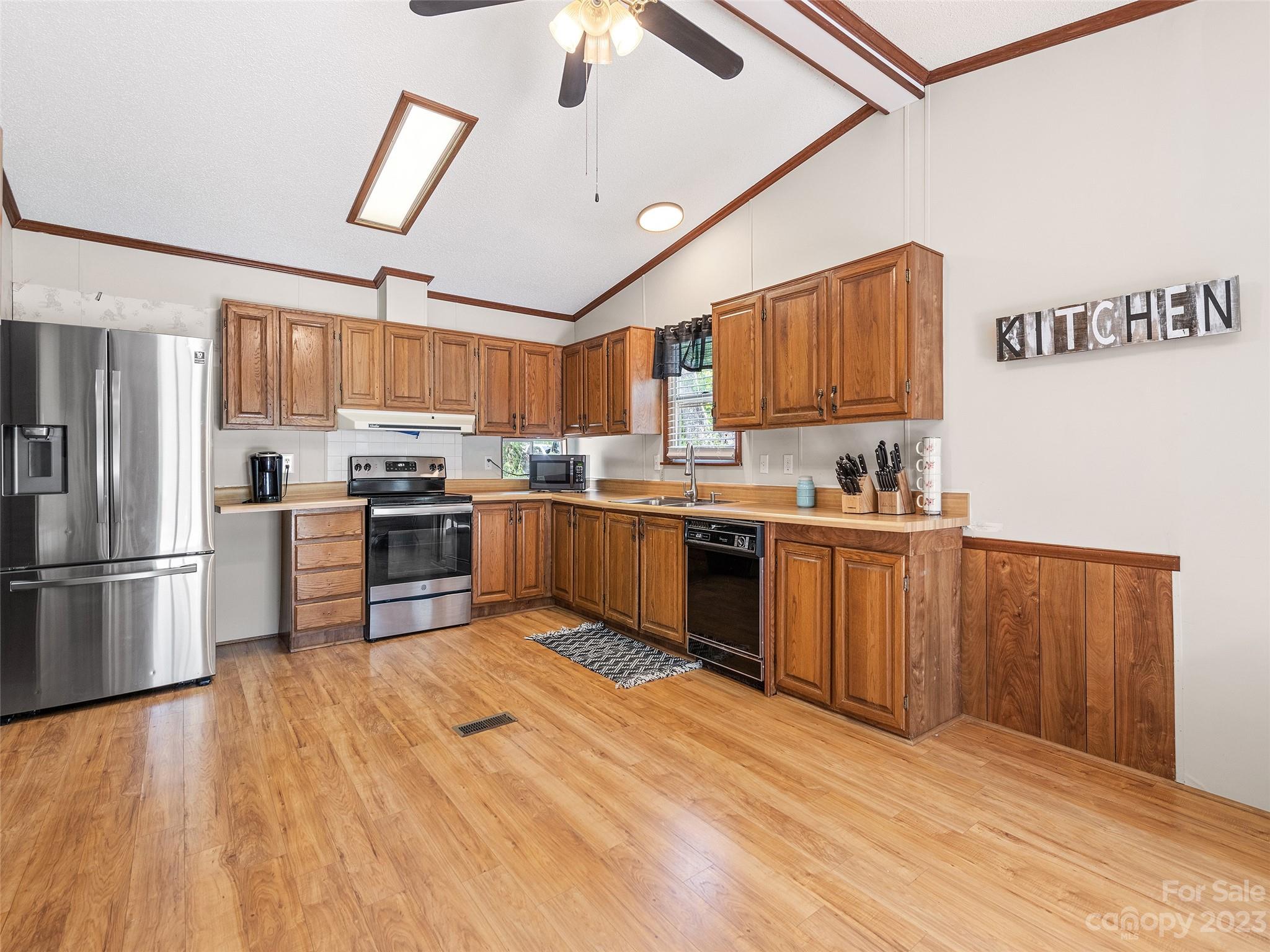 38 Happy Acres Road Waynesville, NC 28785 - Photo 16 of 28 a kitchen with stainless steel appliances granite countertop a refrigerator oven a sink dishwasher and white cabinets with wooden floor