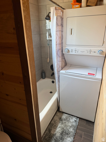 785 Hardscrabble Road Morgan, UT 84050 - Photo 15 of 16 Vertical stacked washer and dryer unit beside a white bathtub with a tiled shower surround and dark bronze fixtures