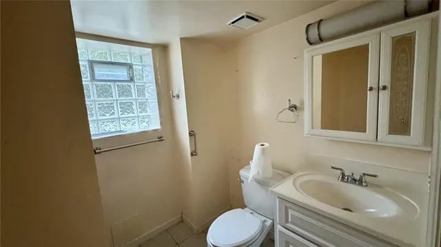 a bathroom with a granite countertop toilet sink and mirror