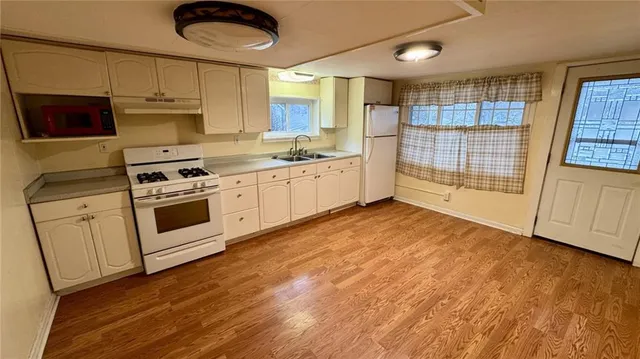 a kitchen with stainless steel appliances granite countertop a stove a sink and white cabinets