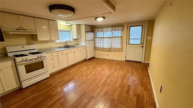 a kitchen with wooden floors and white appliances
