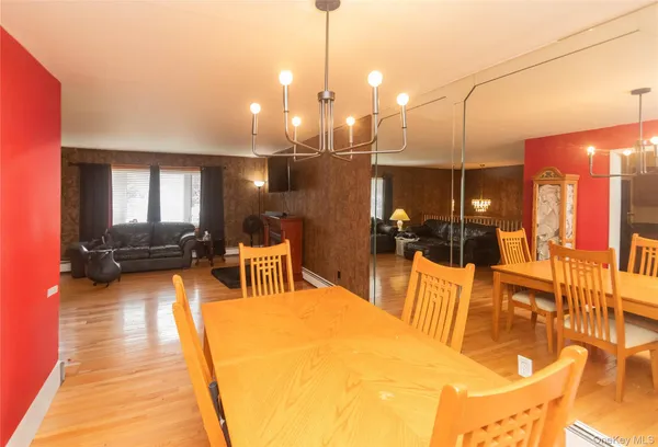 a kitchen with stainless steel appliances granite countertop a sink a stove a dining table and chairs with wooden floor