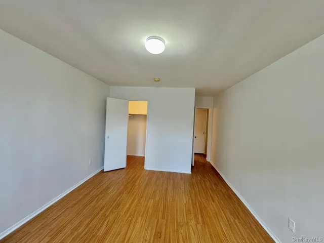 a view of an empty room with wooden floor and closet