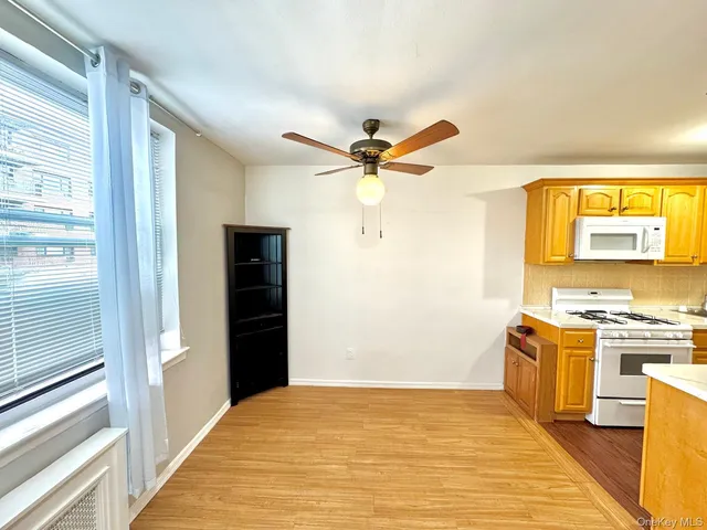 a view of a kitchen with a stove cabinets a ceiling fan and wooden floor