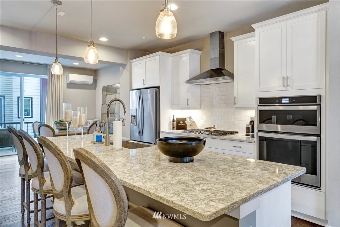 606 237th Street Southeast, Unit C Bothell, WA 98021 - Photo 8 of 27 a kitchen with stainless steel appliances kitchen island granite countertop a stove a refrigerator a oven a dining table and chairs with wooden floor