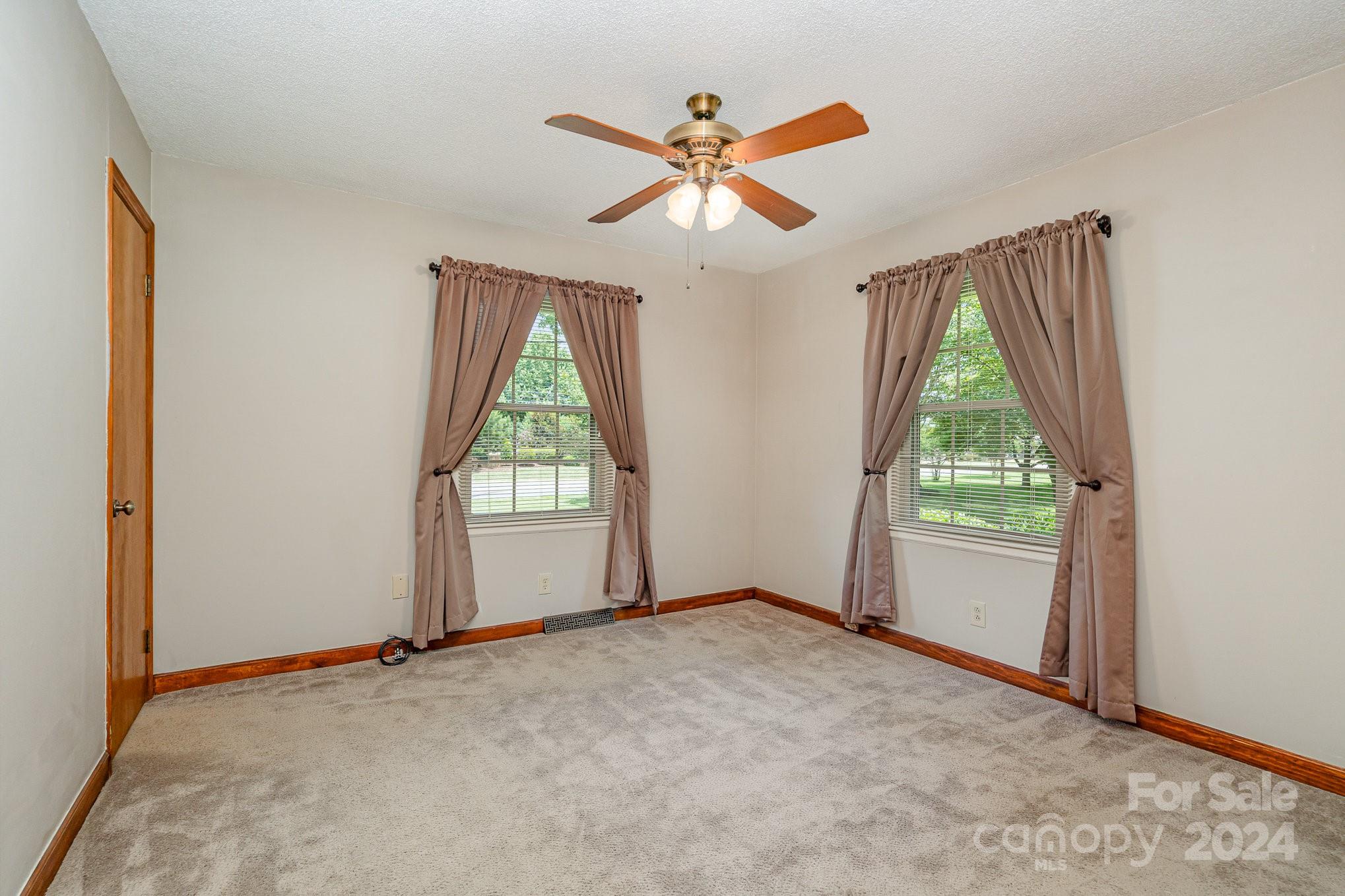 5124 Margaret Wallace Road Matthews, NC 28105 - Photo 15 of 26 an empty room with windows and a ceiling fan