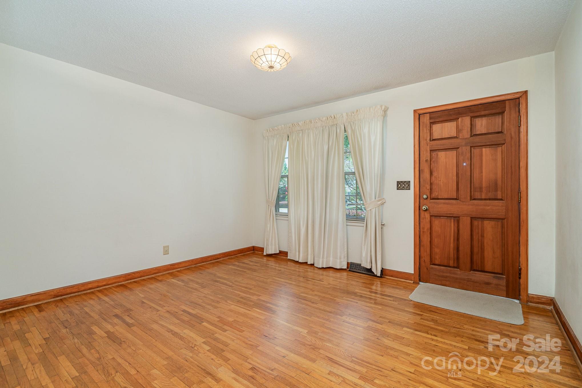5124 Margaret Wallace Road Matthews, NC 28105 - Photo 4 of 26 a view of an empty room with wooden floor and a window