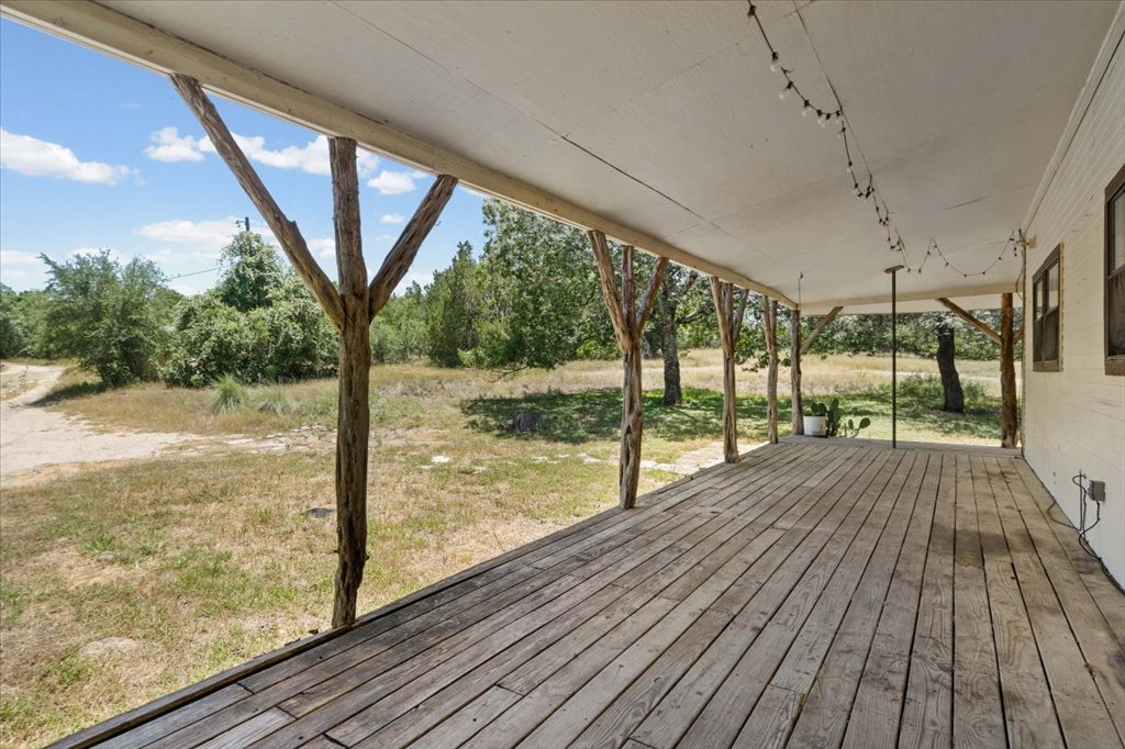555 Harmon Hills Road, Unit A Dripping Springs, TX 78620 - Photo 10 of 29 A spacious wooden deck provides a serene outdoor retreat amidst a verdant landscape.