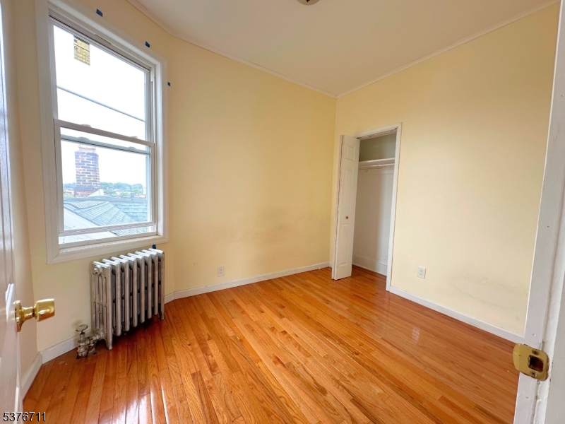182 Knickerbocker Avenue, Unit 2 Paterson, NJ 07503 - Photo 11 of 14 an empty room with wooden floor and windows