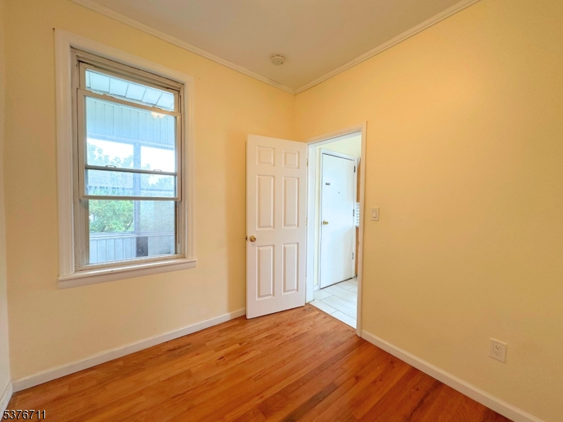 182 Knickerbocker Avenue, Unit 2 Paterson, NJ 07503 - Photo 8 of 14 an empty room with wooden floor and windows
