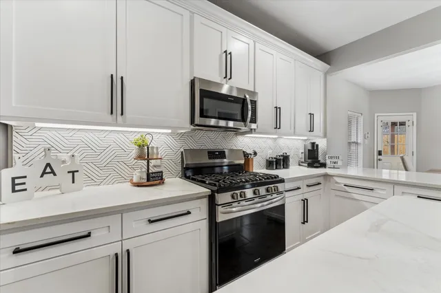 a kitchen with granite countertop a sink stove and microwave