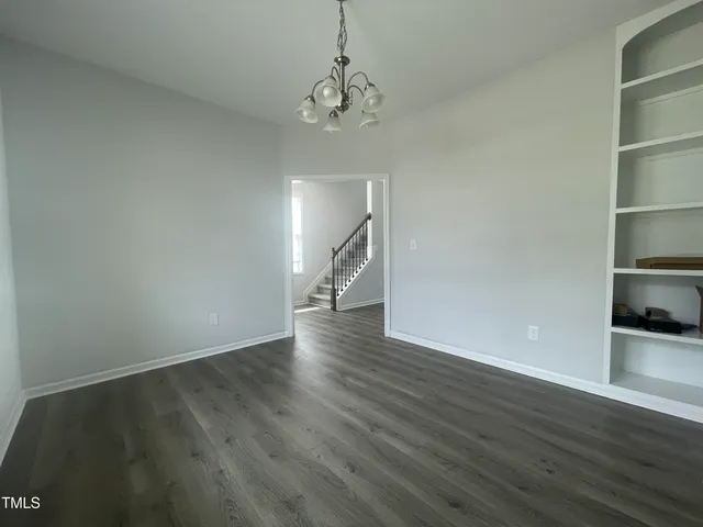 a kitchen with stainless steel appliances granite countertop a stove top oven a sink a refrigerator and white cabinets with wooden floor