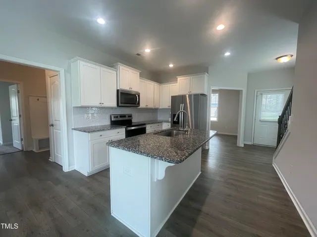 an empty room with wooden floor fireplace and windows