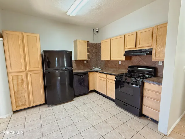 a kitchen with granite countertop a refrigerator stove top oven and sink