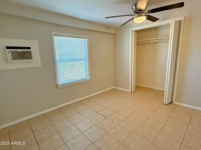 a view of an empty room with window and chandelier fan