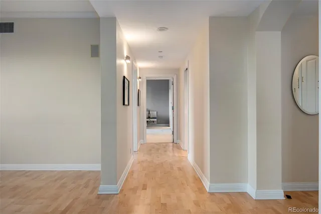 a view of a hallway with wooden floor and a bathroom