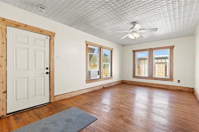 a view of an empty room with window and wooden floor