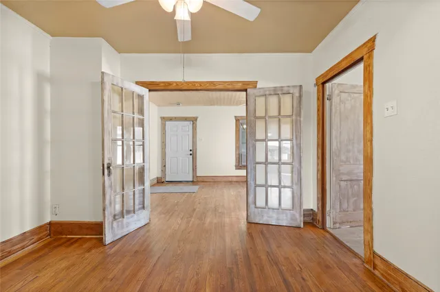 an empty room with wooden floor and a ceiling fan