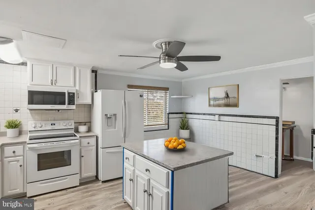 a kitchen with stainless steel appliances a stove a refrigerator and white cabinets