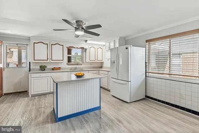 a kitchen with stainless steel appliances a refrigerator a sink and white cabinets
