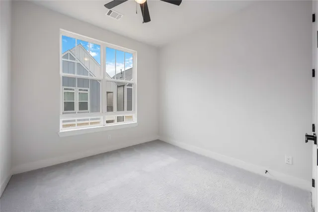 an empty room with windows and chandelier fan
