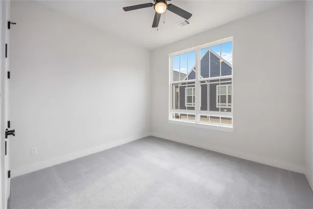 an empty room with chandelier fan and windows