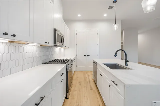 a kitchen with white cabinets a sink and dishwasher