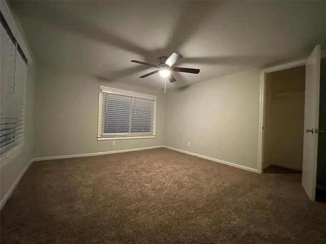 a view of an empty room with a ceiling fan and a window