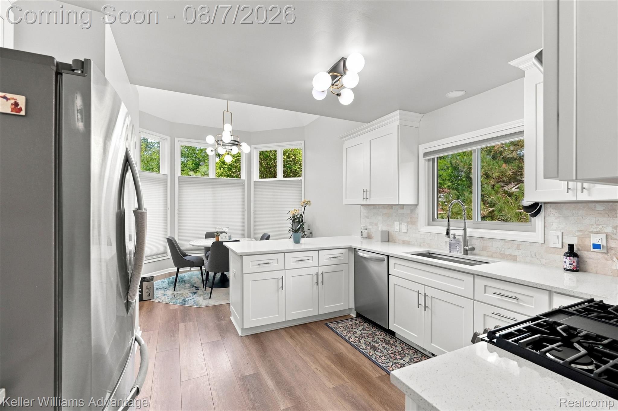5325 Simpson Lake Road West Bloomfield, MI 48323 - Photo 10 of 43 White cabinetry, wood-finish flooring, stainless steel appliances, stone countertops, and a tiled backsplash