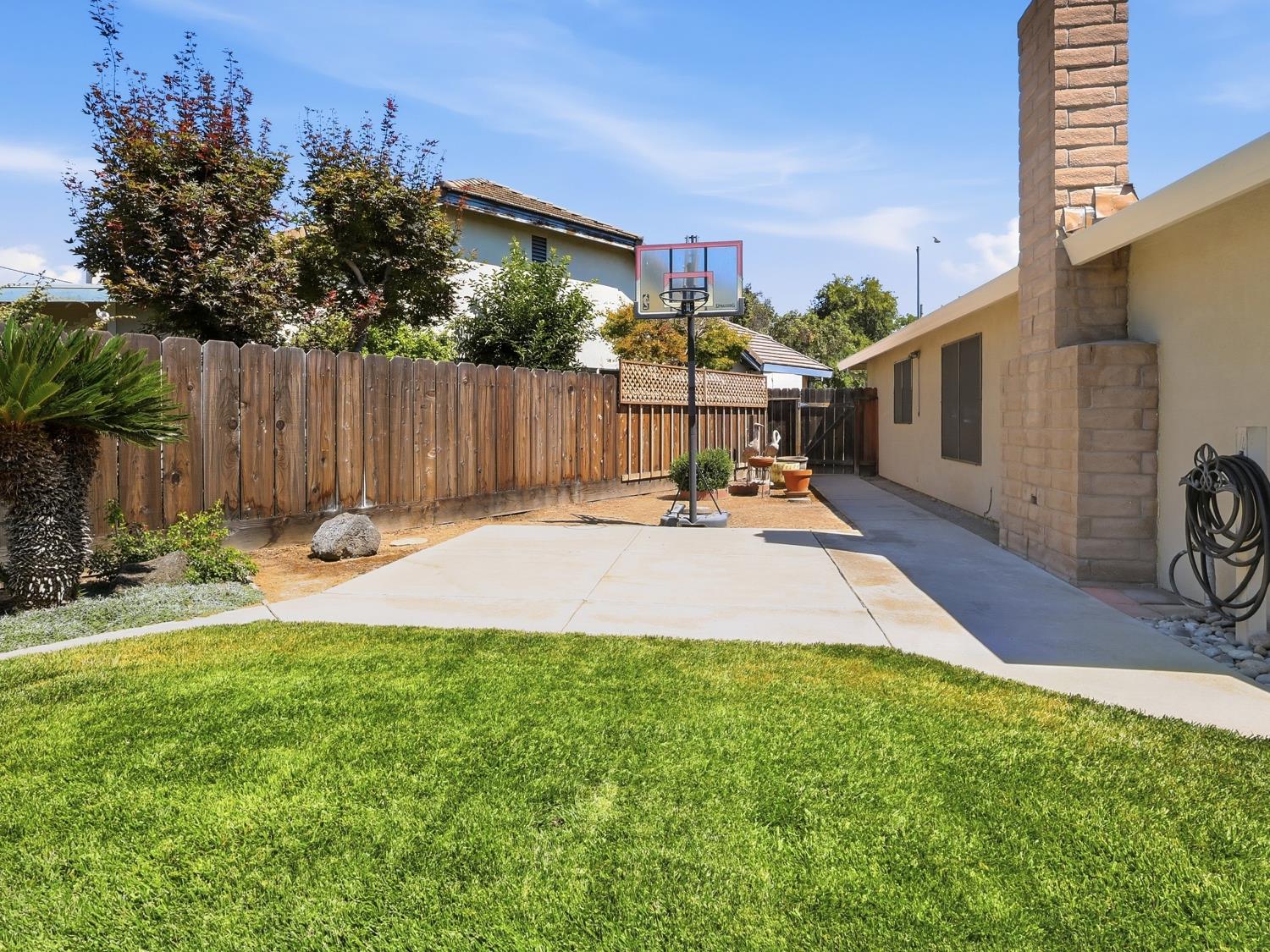 900 Multnomah Drive Modesto, CA 95350 - Photo 25 of 34 Expansive backyard featuring a lush lawn, concrete patio, privacy fencing, and mature trees