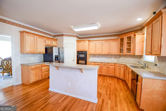 a large kitchen with stainless steel appliances granite countertop a stove a sink dishwasher and a refrigerator with wooden floor