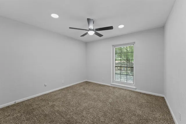 an empty room with chandelier fan and windows