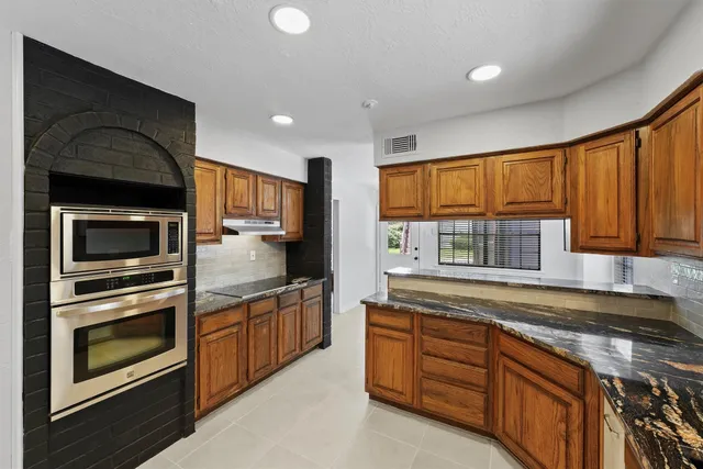 a kitchen with stainless steel appliances granite countertop wooden cabinets a stove top oven a sink and dishwasher