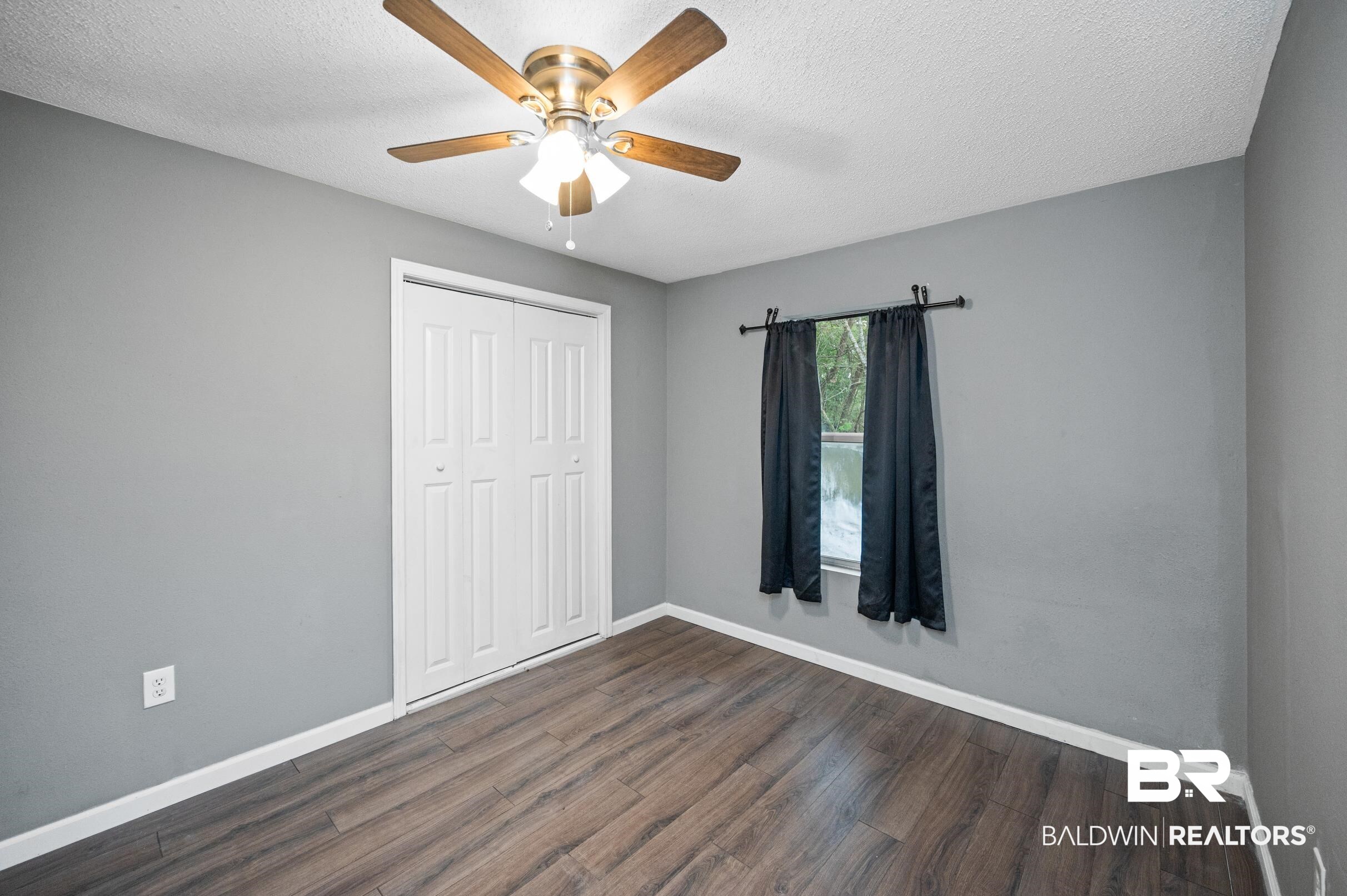 906 North Cedar Street Foley, AL 36535 - Photo 18 of 24 Unfurnished bedroom featuring a closet, a textured ceiling, ceiling fan, and dark hardwood / wood-style floors