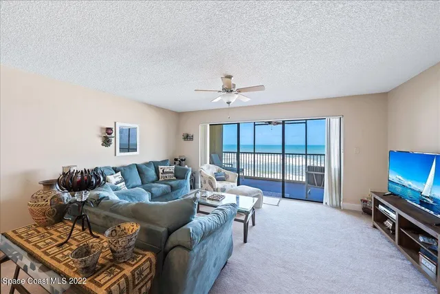 a living room with furniture a flat screen tv and a floor to ceiling window