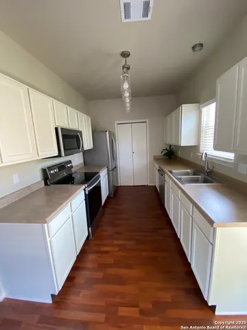a kitchen with granite countertop a sink wooden floor and stainless steel appliances