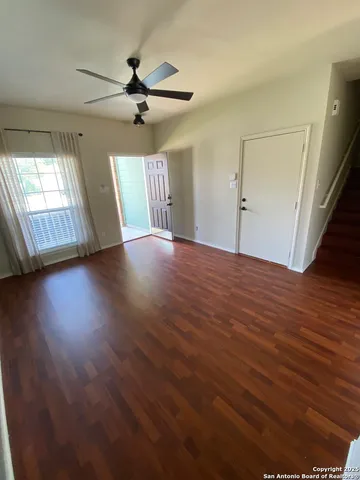 an empty room with wooden floor fan and windows
